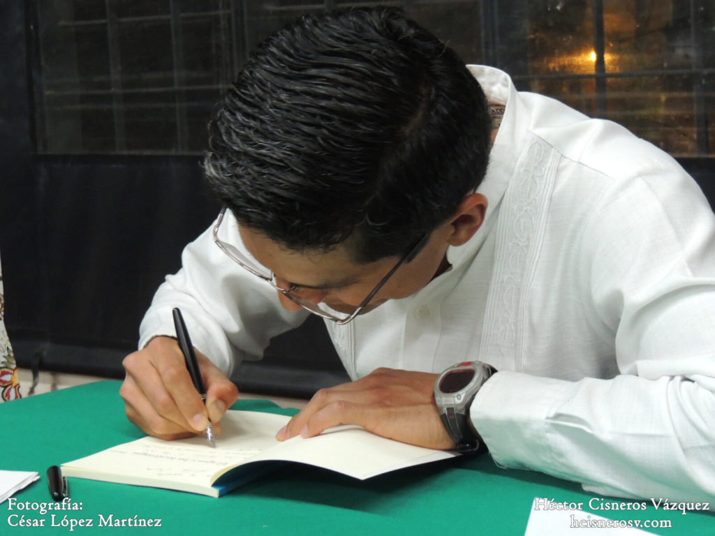 Hector Cisneros firmando libros. Presentación del poemario El agua y las luciernagas en la UACM.